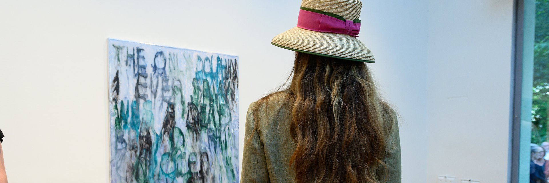 Eine Dame mit Hut besichtigt ein Bild in einer Gallery während der sommer.frische.kunst in Bad Gastein