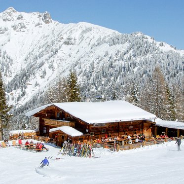 Schneebedeckte Skihütte mit Bergpanorama im Hintergrund