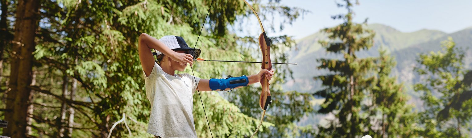 Kind zielt mit Pfeil und Bogen beim Bogenschießen im Gasteinertal.