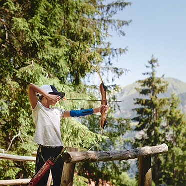Kind zielt mit Pfeil und Bogen beim Bogenschießen im Gasteinertal.