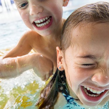 Kinder lachen und spielen im Schwimmbad einer Therme im Gasteinertal im Salzburger Land