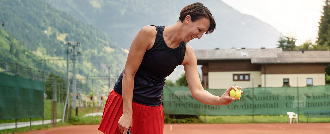 Frau spielt Tennis auf einem Tennisplatz im Gasteinertal.