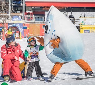 Skilehrer, Kinder und das Maskottchen Gasti auf Skiern im Skigebiet Gastein.